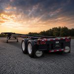 Trailer chassis parked in an outdoor lot at sunset, shown from a rear angle with dramatic clouds and warm evening light matching the style of other commercial trailer images.